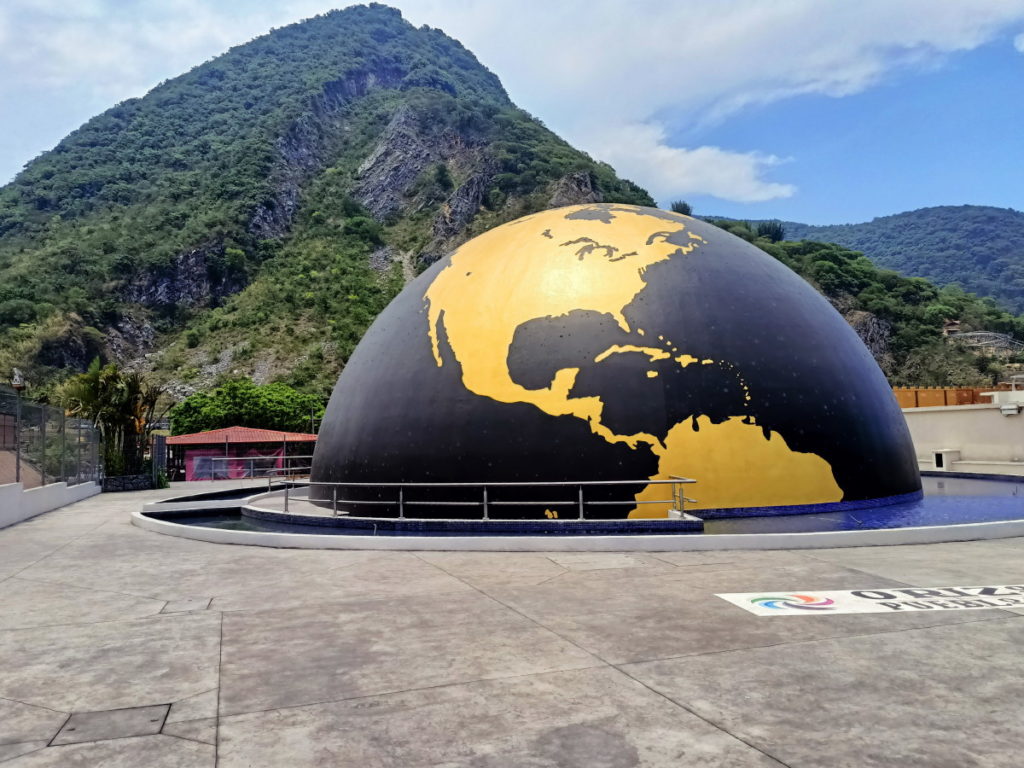 The planetarium dome is picturesque against a backdrop of verdant mountains.