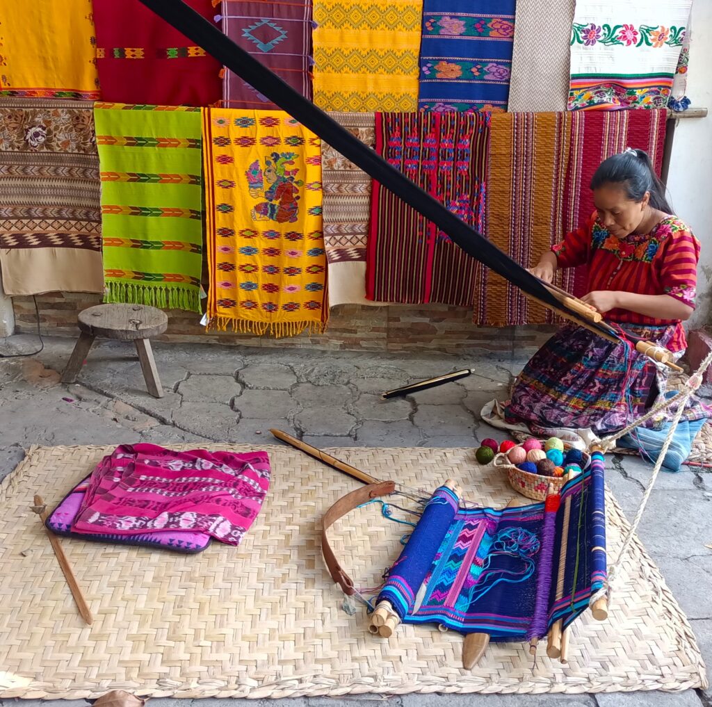 The hand woven textiles are very colorful.  Many women still weave, using a backstrap loom. pictured.